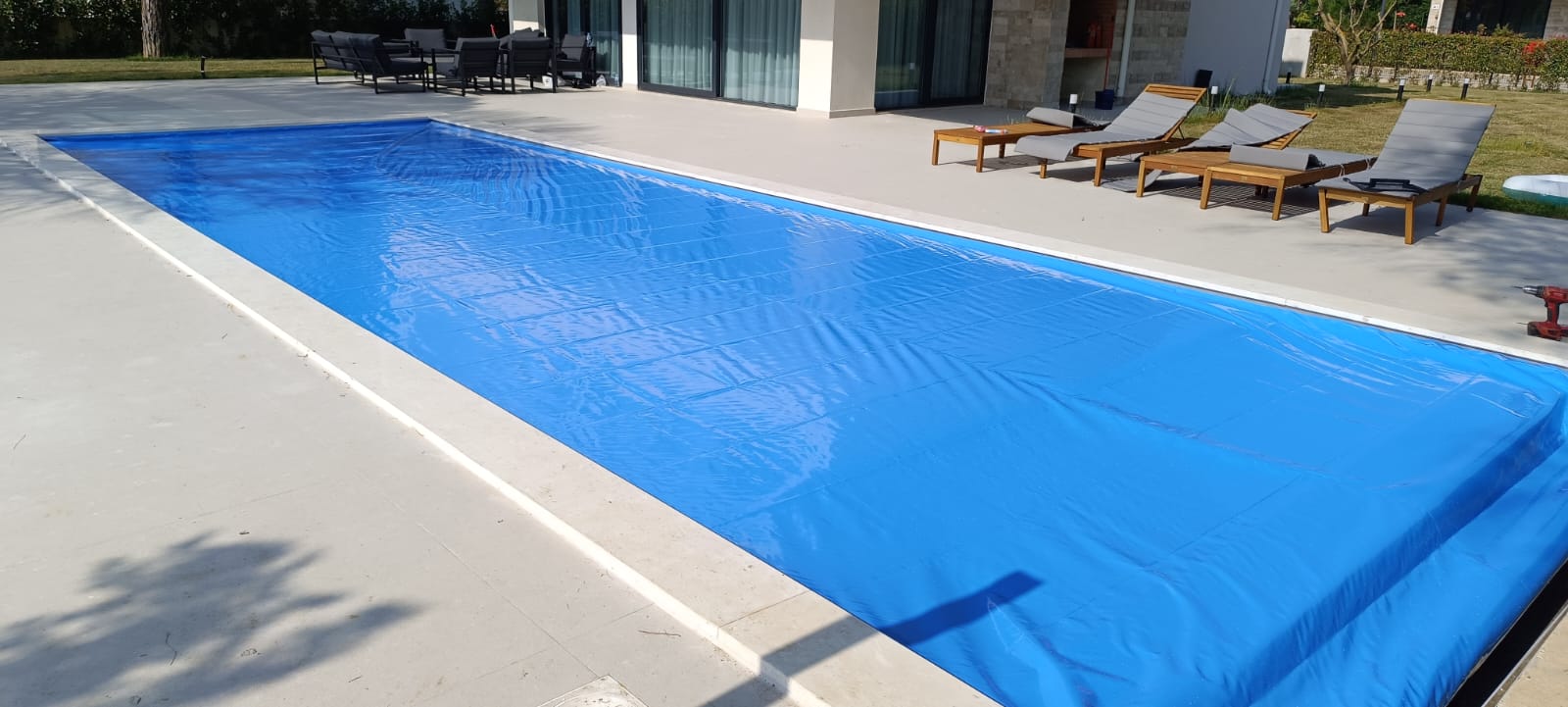 Αυτόματο κάλυμμα πισίνας PoolLock εγκατεστημένο σε μοντέρνα πισίνα για ασφάλεια και εξοικονόμηση ενέργειας.
